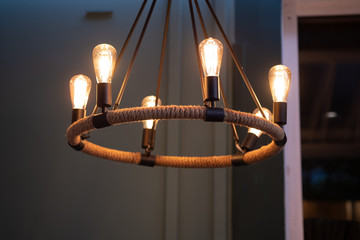 Vintage wicker chandelier in the cafe. Glowing lamps.