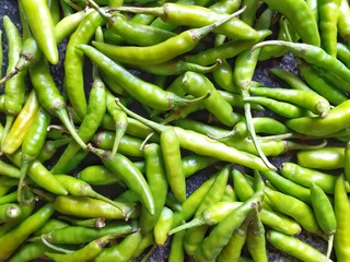 Green chillies background. Closeup image of peppers on the floor.