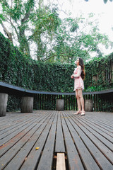 Young beautiful asian woman in pink dress relaxing in wooden hall with plant
