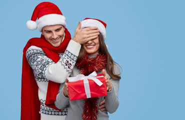Romantic couple in Santa hats carrying surprise gift box