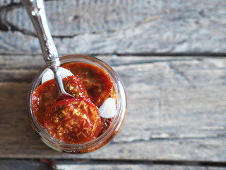 dried tomatoes in a glass jar with a fork in olive oil