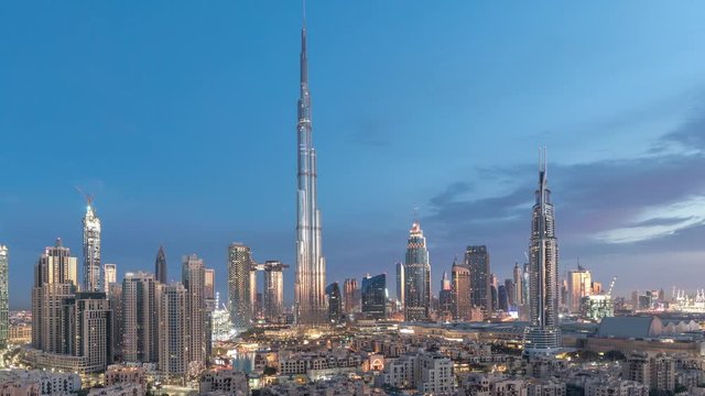 Dubai Downtown skyline night to day transition timelapse with Burj Khalifa and other skyscrapers paniramic view from the top in Dubai, United Arab Emirates. Traffic on circle road. Modern and