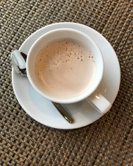 The white ceramic cup of hot coffee is on the table.