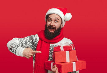 Happy hipster showing stack of Christmas presents