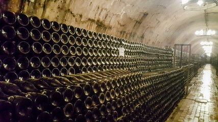 Wine bottles in the cellar. Wine cellar at the factory. Interior of cellar with bottles of old bottles of champagne.