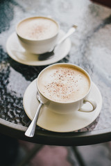 Two cups of cappuccino and two brownie desserts.