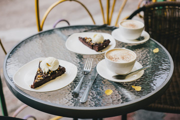 Two cups of cappuccino and two brownie desserts.