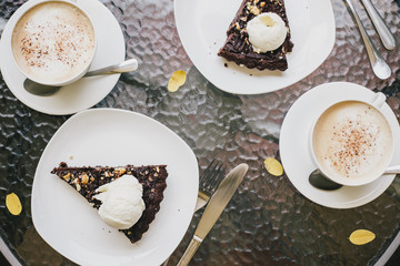 Two cups of cappuccino and two brownie desserts.