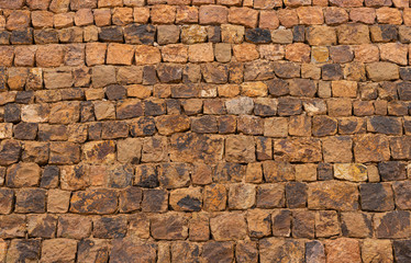 Old stone block wall in orange tones of the old gold mines of Rodalquilar in the province of Almeria in Spain.
