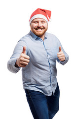 Smiling redhead man with a beard in a blue shirt and in a Santa Claus hat. Close-up. Isolated over white background. Vertical.