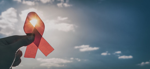 Red ribbon symbol of AIDS and HIV disease. - obrazy, fototapety, plakaty