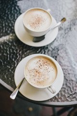 Two cups of cappuccino and two brownie desserts.