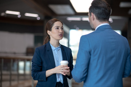 Business lady talking to her business partner while drinking coffee