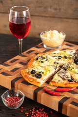 Sliced pizza and vegetables on a wooden cutting board.