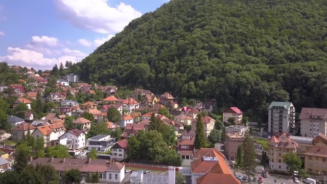 Aerial view of Brasov city, medieval town situated in Transylvania, Romania. Old architecture surrounded with big Carpathian mountains covered with dense green forest.