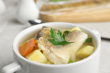 Delicious fish soup in bowl on table, closeup view