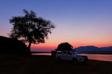 Foto op Aluminium African safari in own cars with tents on the roof, sleeping on the riverside of Zambezi in Zimbabwe, star trails on the sky and night picture © phototrip.cz