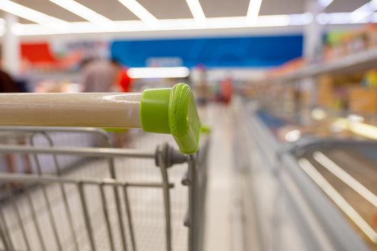 Empty shopping cart in super market or  convenience store concept and shelves in frozen food corner on blurry for background