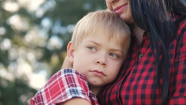 happy family mom and son sad child concept. mom tender childhood video. slow motion video. a mom brunette girl protects caress gently hugs takes lifestyle care of the son blonde boy outdoors