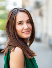 Fashion model wearing green overall posing outdoor. Young beautiful brunette caucasian woman walking summer streets. Beautiful girl, urban portrait.