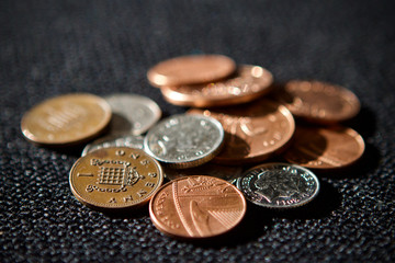 Pile of British coins on a black textured background