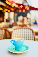 Cup of fresh hot espresso coffee on table of traditional Parisian outdoor cafe in Paris
