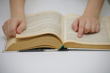 Naklejka premium Little girl reads big book against white background and drives down lines with a finger