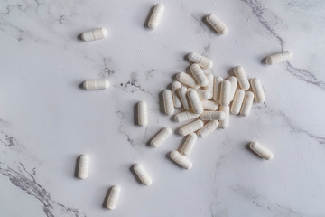 painkillers and drug abuse concept with close up on a bottle of prescription drugs and pill capsules falling out of it on a white marble table
