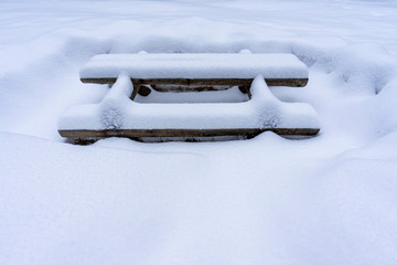 Table with a bench under the snow.