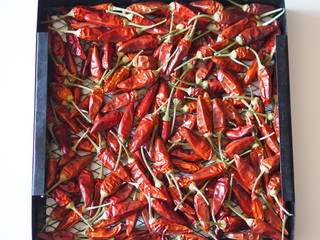 Hot chili peppers are dried on a black wire rack from the dryer