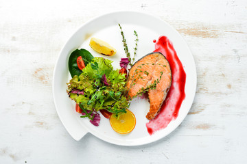 Baked salmon steak and fresh vegetables on a plate. Top view. Free copy space.