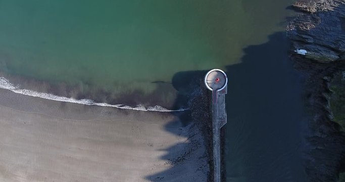 Aerial view of harbour wall and waves on a beach at looe