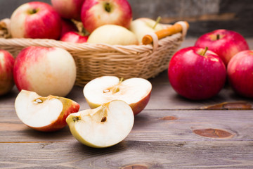 Naklejka na ściany i meble Sliced apple and ripe red apples on a wooden table and in a basket