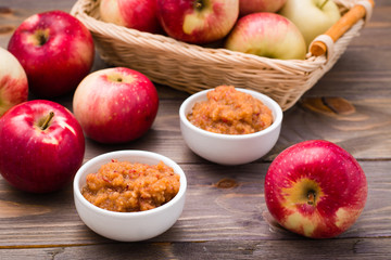 Fresh applesauce in bowls and red apples on a wooden table. Baby food