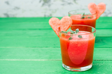 Fresh watermelon blended drink with mint leaves and a heart of watermelon in glasses on a wooden table. Ready-to-eat drink. Copy space