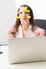 Gestresste Büroangestellte mit Post-Its im Gesicht