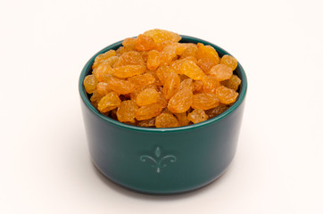 White or golden raisins in a blue ceramic bowl on a white background. Healthy sweets concept. Closeup