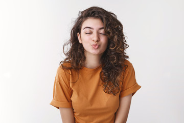 Fototapeta premium Girl folding lips smiling excited close eyes reach camera have first kiss anticipating feel boyfriend lips standing white background tender romantic relationship moment, white background
