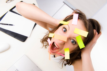 Gestresste Büroangestellte mit Post-Its im Gesicht