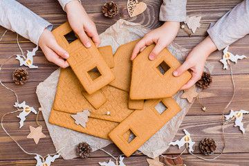 Parts of a disassembled Christmas gingerbread house in children's hands and Christmas decorations...