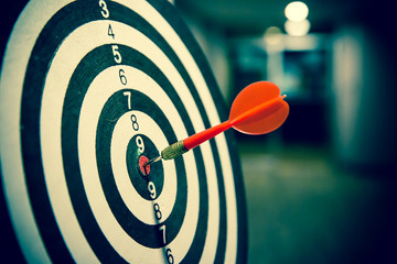 Red dart arrow  hitting in the target center of dartboard on bullseye for Business focus...
