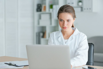 Female doctor working on laptop in clinic