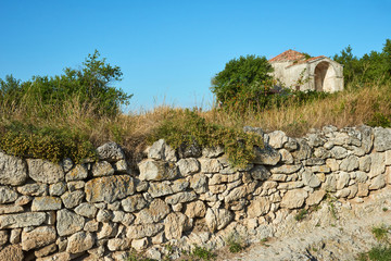 Stone wall on the street of an ancient abandoned city. The ruins of the old city. Sunny summer day, clear blue sky.