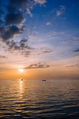Amazing summer sunset view on the beach. Beautiful blazing sunset landscape at black sea and orange sky above it with awesome sun golden reflection on calm waves as a background.