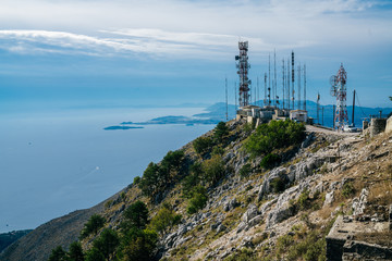 Fototapeta na wymiar Telecommunication antennas on the edge of the mountain with sea on the background