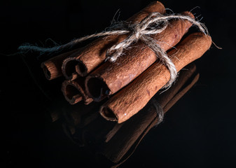 Dry cinnamon sticks with reflection on shiny black background