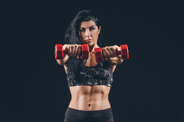 Sporty muscular woman with dumbbells on dark background