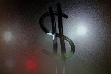 a dollar sign written on night wet window glass close-up
