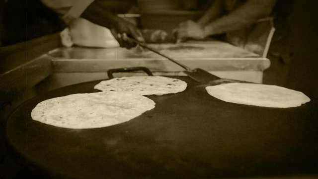 Old film effect accelerated footage of Indian street cooks (vendors) preparing chapatis (Indian breads)