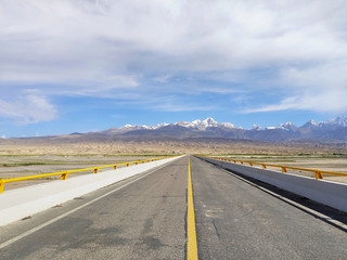 Asphalt highway stretching towards snow mountain